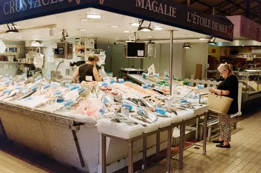 Étal de poissonnerie sous une halle de marché.